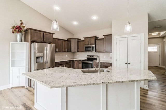 4901 NW 15th St, Ankeny, IA 50023 - kitchen with light wood finished floors, stainless steel appliances, dark brown cabinets, vaulted ceiling, and light stone countertops
