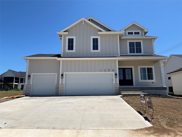 1258 S 92nd St, West Des Moines, IA 50266 - view of front of house with driveway, stone siding, board and batten siding, and an attached garage