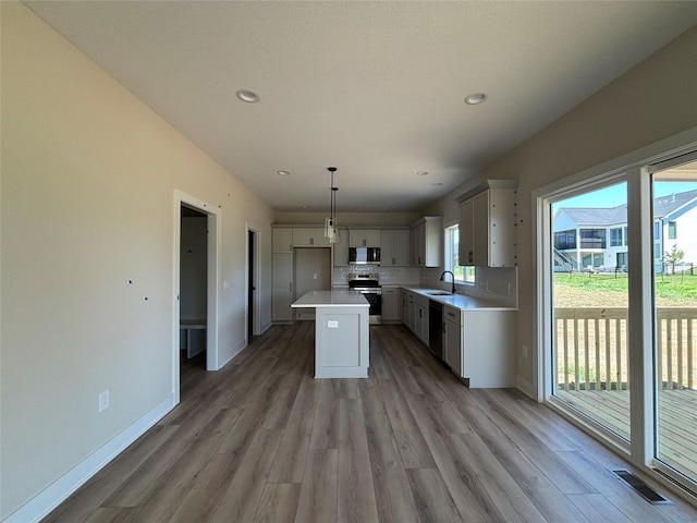 1258 S 92nd St, West Des Moines, IA 50266 - kitchen featuring stainless steel appliances, light wood-style floors, light countertops, backsplash, and a kitchen island