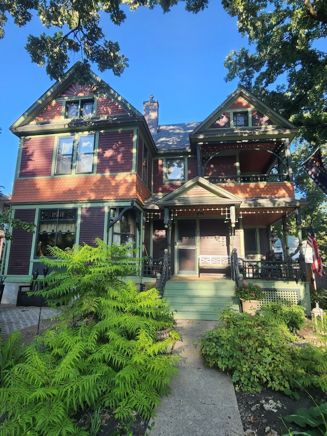 view of front of house featuring a chimney, a porch, and a balcony