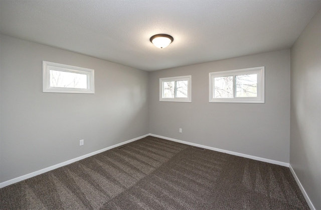 empty room featuring dark carpet and baseboards