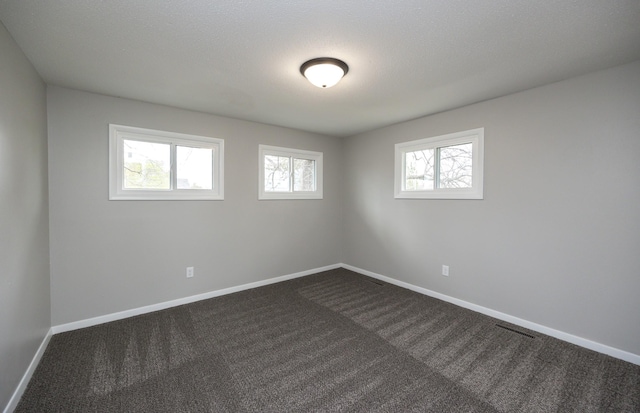 empty room featuring baseboards and dark colored carpet