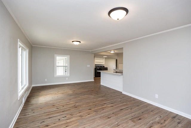 unfurnished living room with baseboards, crown molding, and dark wood-style floors