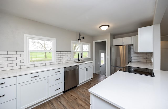 kitchen with stainless steel appliances, a sink, tasteful backsplash, light countertops, and dark wood-type flooring