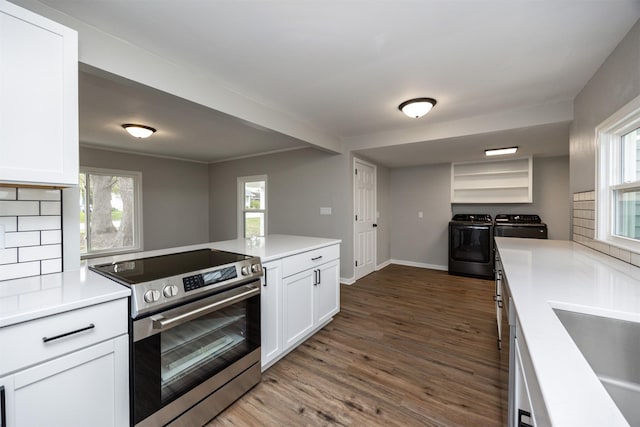kitchen with dark wood finished floors, washing machine and dryer, stainless steel electric range, white cabinetry, and light countertops