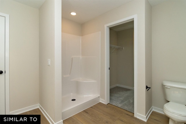 4312 NE 8th St, Ankeny, IA 50021 - bathroom featuring wood finished floors, toilet, a walk in closet, baseboards, and a shower