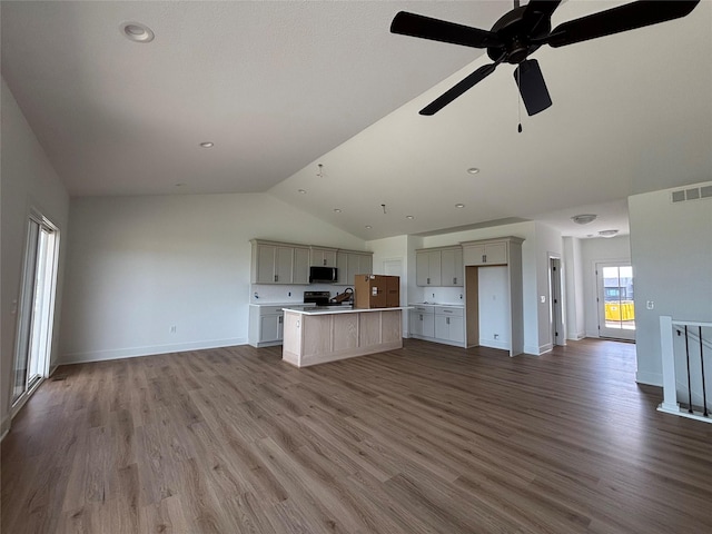 4655 178th St, Urbandale, IA 50263 - unfurnished living room featuring vaulted ceiling, ceiling fan, wood finished floors, baseboards, and a sink
