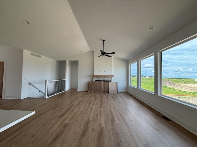 4655 178th St, Urbandale, IA 50263 - unfurnished living room featuring ceiling fan, vaulted ceiling, wood finished floors, a stone fireplace, and baseboards