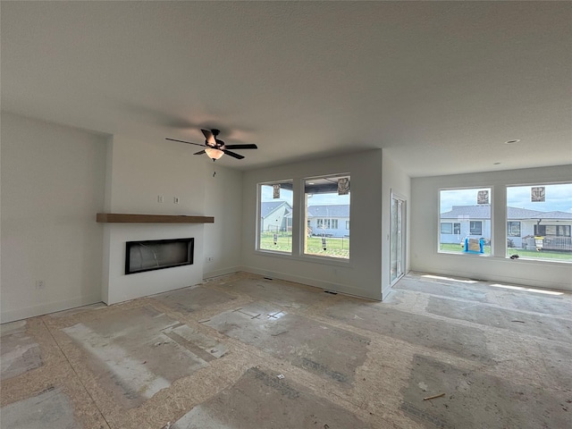 unfurnished living room featuring baseboards, a fireplace, and ceiling fan