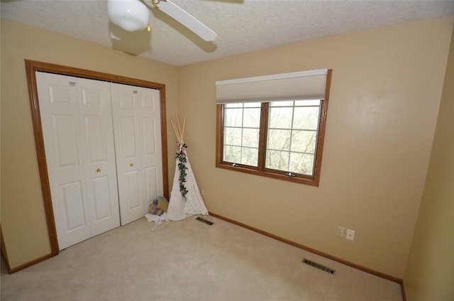 unfurnished bedroom featuring carpet floors, a textured ceiling, visible vents, and a closet
