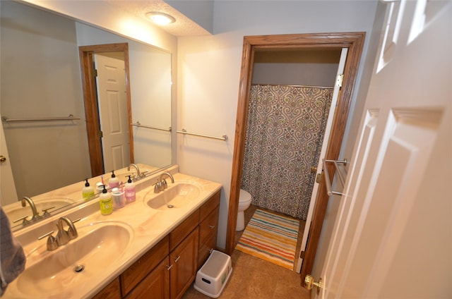 full bath with a sink, double vanity, and toilet