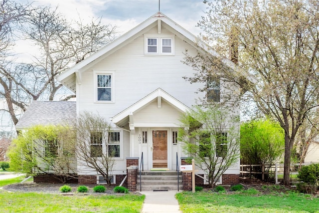 view of front facade featuring roof with shingles and a front yard