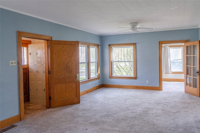 unfurnished room with baseboards, carpet, ceiling fan, and crown molding