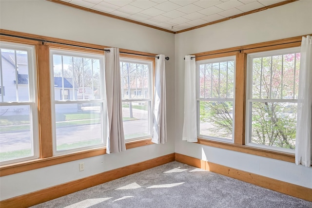 empty room with carpet floors, a healthy amount of sunlight, baseboards, and ornamental molding