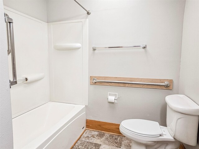 bathroom with shower / bathing tub combination, stone finish flooring, and toilet
