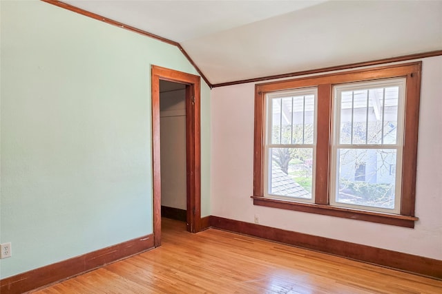 empty room with lofted ceiling, plenty of natural light, baseboards, and light wood-type flooring
