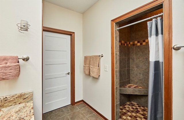 full bath featuring a tile shower, tile patterned flooring, and baseboards