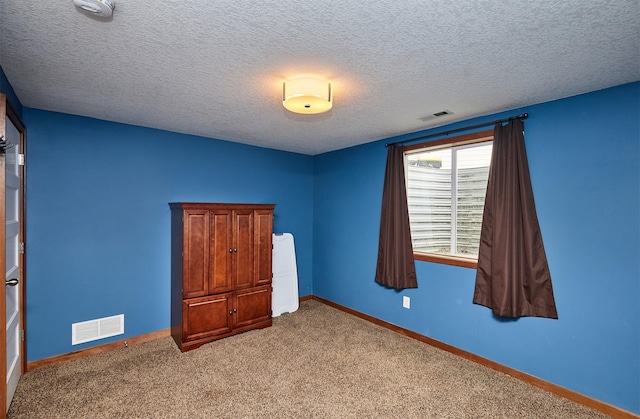 unfurnished bedroom with baseboards, carpet flooring, a textured ceiling, and visible vents