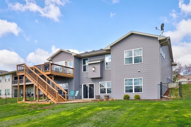 rear view of house featuring a wooden deck, a lawn, stairs, and fence
