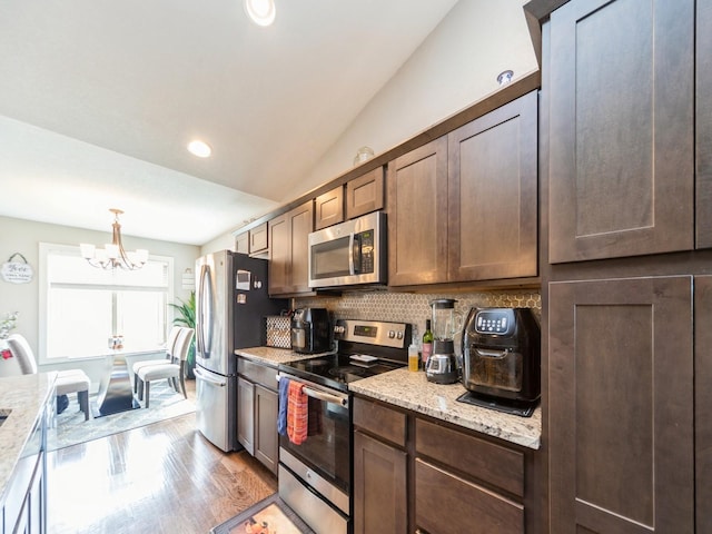1110 NE 15th Ln, Ankeny, IA 50021 - kitchen with light wood finished floors, dark brown cabinetry, an inviting chandelier, decorative backsplash, and appliances with stainless steel finishes
