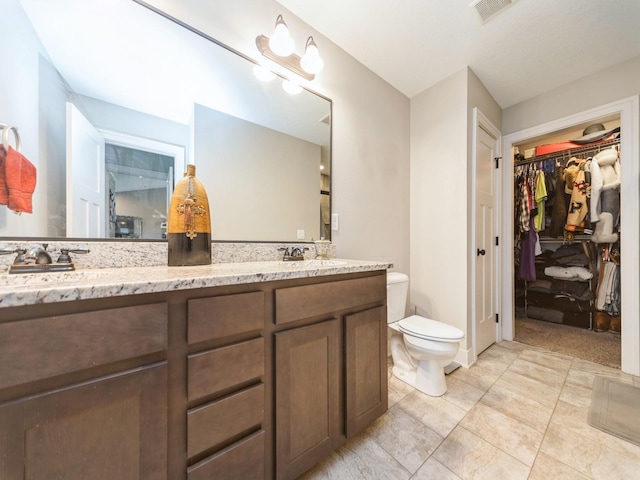 1110 NE 15th Ln, Ankeny, IA 50021 - bathroom with double vanity, visible vents, toilet, a sink, and a walk in closet