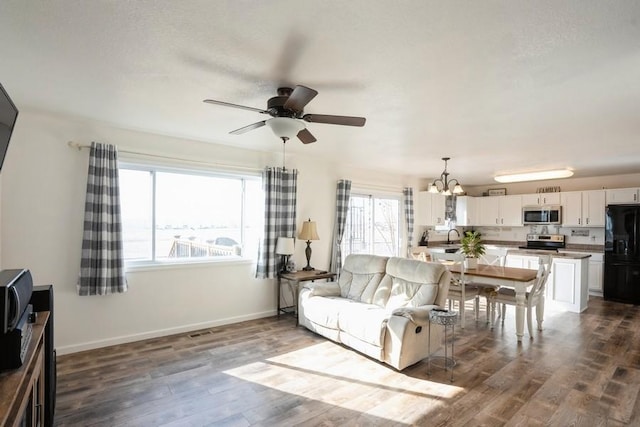 717 37th St SW, Bondurant, IA 50035 - living room with ceiling fan with notable chandelier, baseboards, dark wood-style floors, and visible vents