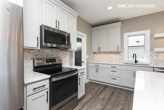 530 Walnut Dr, Huxley, IA 50124 - kitchen with appliances with stainless steel finishes, backsplash, dark wood-type flooring, recessed lighting, and light stone counters