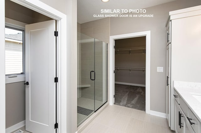 530 Walnut Dr, Huxley, IA 50124 - bathroom featuring a stall shower, vanity, a spacious closet, and tile patterned flooring