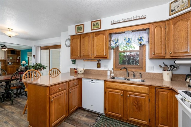 4508 49th St, Des Moines, IA 50310 - kitchen with white appliances, a sink, a textured ceiling, a peninsula, and brown cabinets