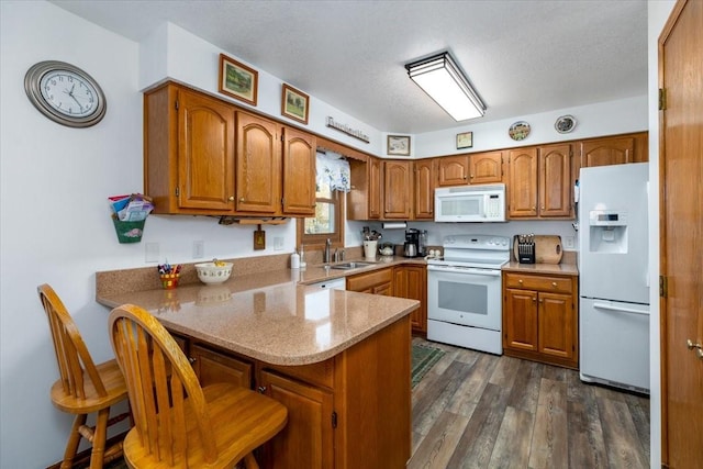 4508 49th St, Des Moines, IA 50310 - kitchen featuring white appliances, a peninsula, a sink, brown cabinets, and dark wood-type flooring