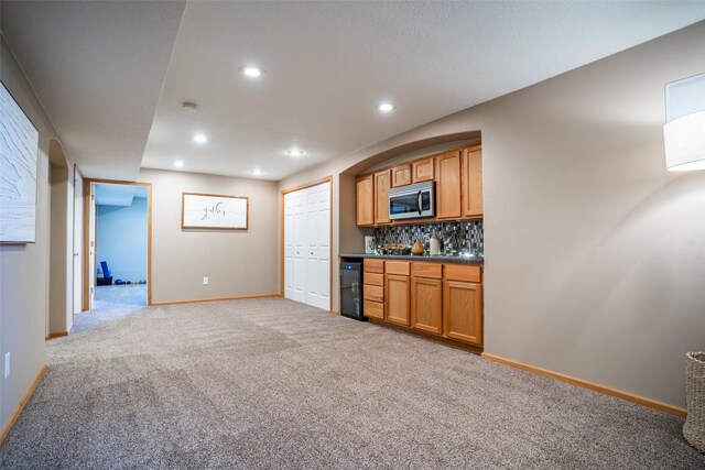748 76th St, West Des Moines, IA 50266 - kitchen with dark countertops, tasteful backsplash, light colored carpet, stainless steel microwave, and baseboards