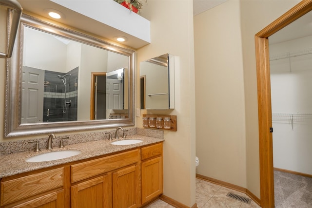 748 76th St, West Des Moines, IA 50266 - bathroom with a tile shower, toilet, double vanity, a spacious closet, and baseboards