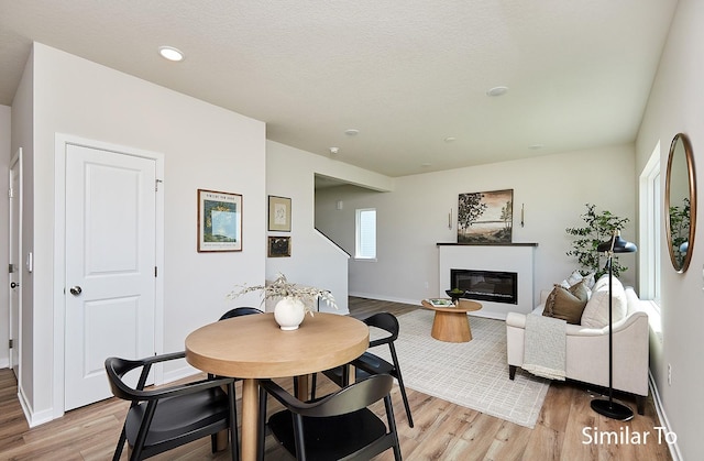 dining area with recessed lighting, a glass covered fireplace, light wood-type flooring, and baseboards