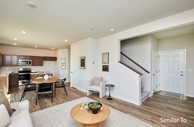 living area featuring baseboards, wood finished floors, and stairs