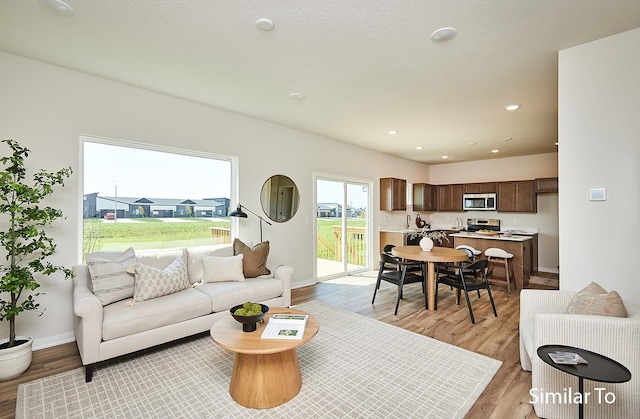 living room with recessed lighting, light wood-type flooring, and baseboards