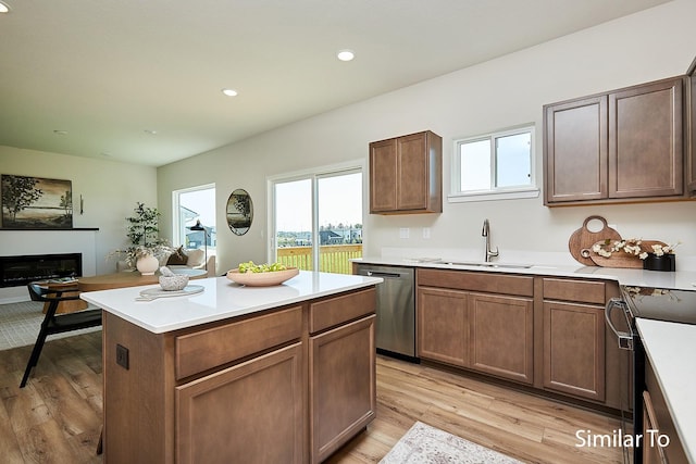kitchen with stainless steel dishwasher, light wood-style flooring, a sink, black range with electric cooktop, and light countertops