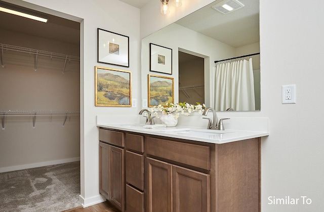 full bathroom with a walk in closet, a sink, visible vents, and double vanity