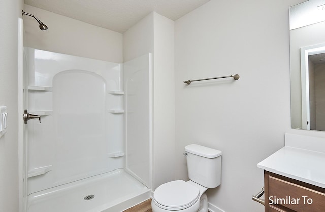 bathroom with baseboards, toilet, vanity, and a shower