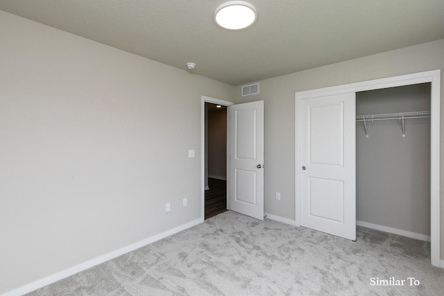 unfurnished bedroom with a closet, carpet, visible vents, and baseboards