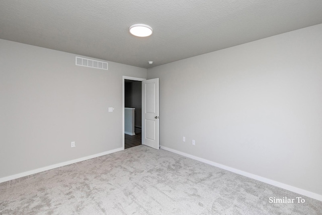 carpeted spare room featuring baseboards and visible vents