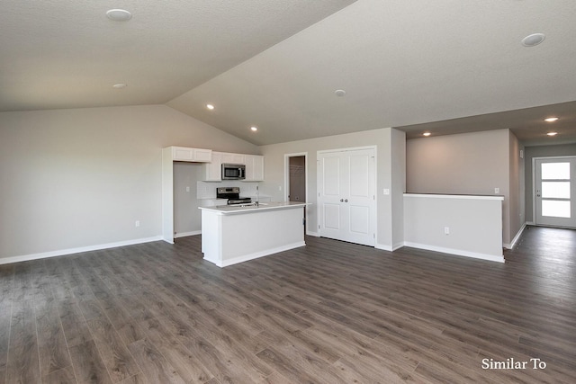 kitchen featuring vaulted ceiling, appliances with stainless steel finishes, open floor plan, and white cabinetry