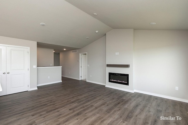 unfurnished living room with dark wood finished floors, vaulted ceiling, a glass covered fireplace, and baseboards