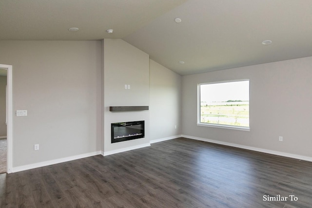 unfurnished living room featuring dark wood-type flooring, a glass covered fireplace, vaulted ceiling, and baseboards