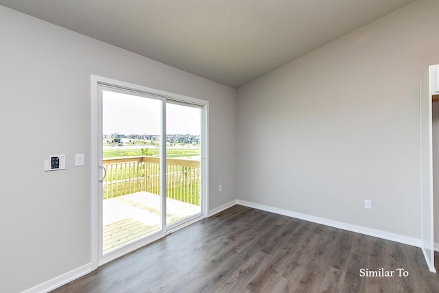 empty room featuring dark wood finished floors, vaulted ceiling, and baseboards