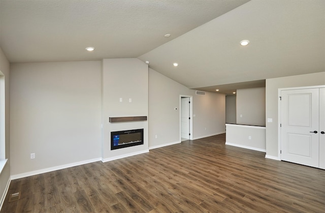 635 NW Compass Ave, Waukee, IA 50263 - unfurnished living room with dark wood-type flooring, vaulted ceiling, a glass covered fireplace, and recessed lighting