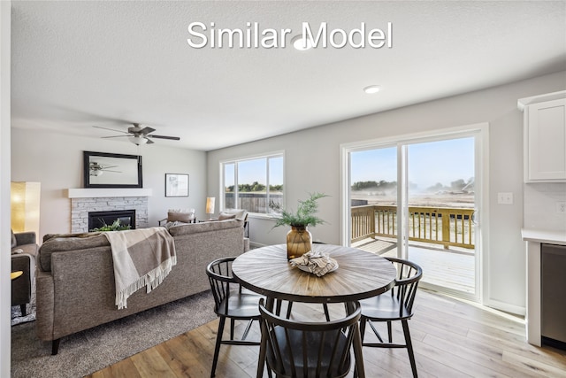 4215 NW 17th Ct, Ankeny, IA 50023 - dining space featuring light wood-style flooring, a stone fireplace, and a ceiling fan
