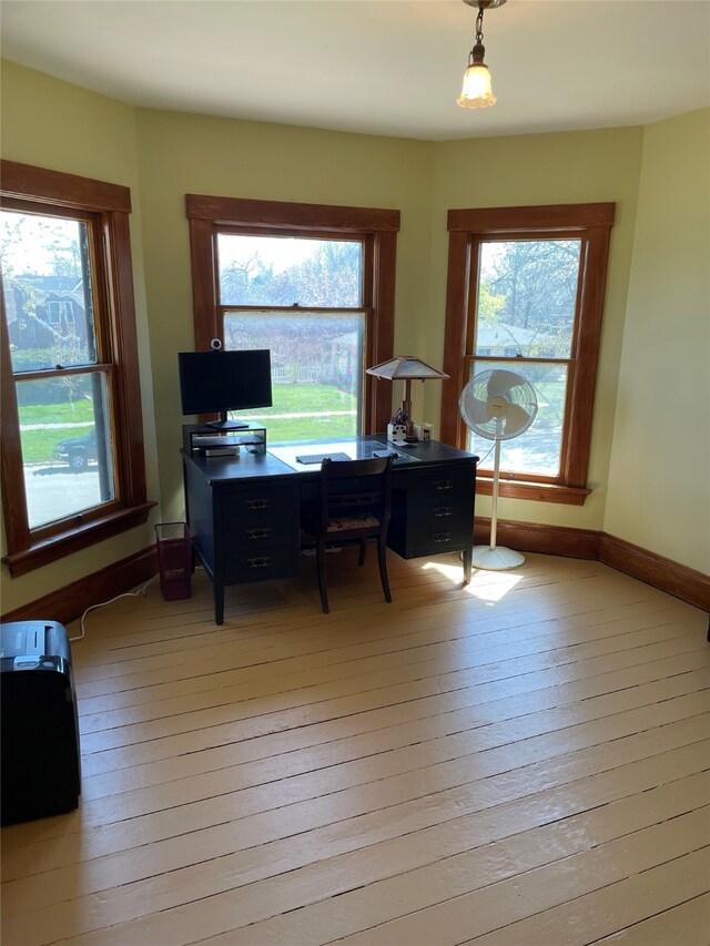 home office with light wood-style flooring, baseboards, and a healthy amount of sunlight