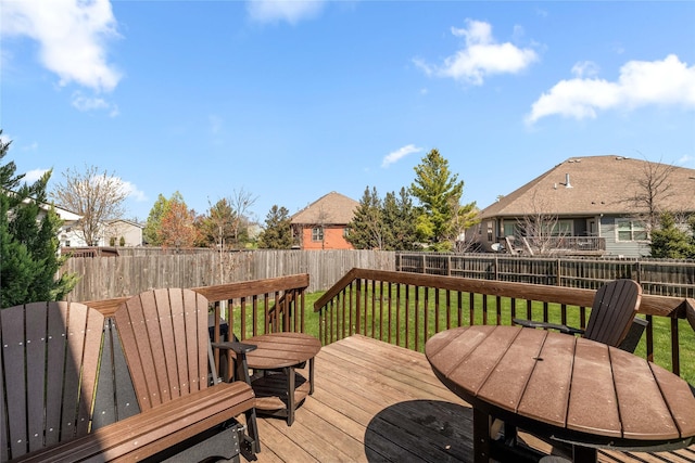 deck with outdoor dining space, a lawn, and a fenced backyard