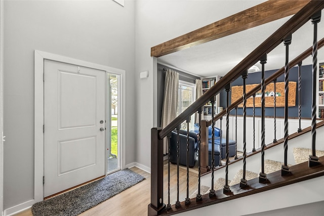 entrance foyer with baseboards, wood finished floors, and stairway