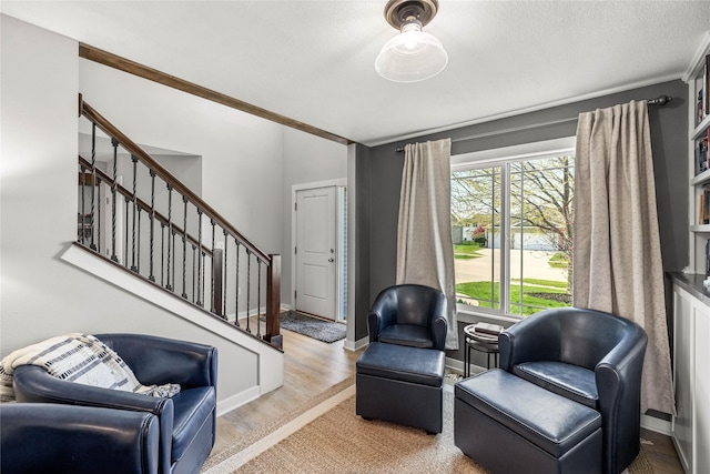 sitting room featuring baseboards and stairs